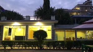 Un edificio moderno con amplios ventanales y un interior luminoso, rodeado de vegetación.