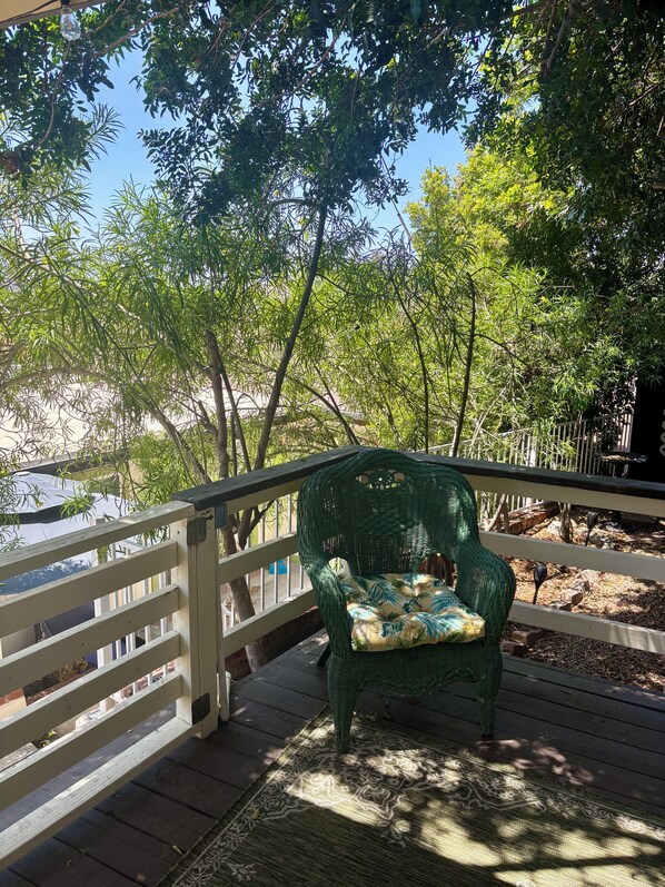 A wooden deck with a wicker chair and a patterned rug.