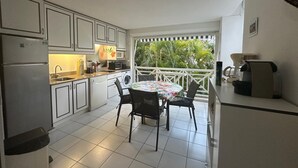Una cucina funzionale con mobili bianchi, un tavolo da pranzo con sedie, una macchina da caffè e vista sul verde circostante.