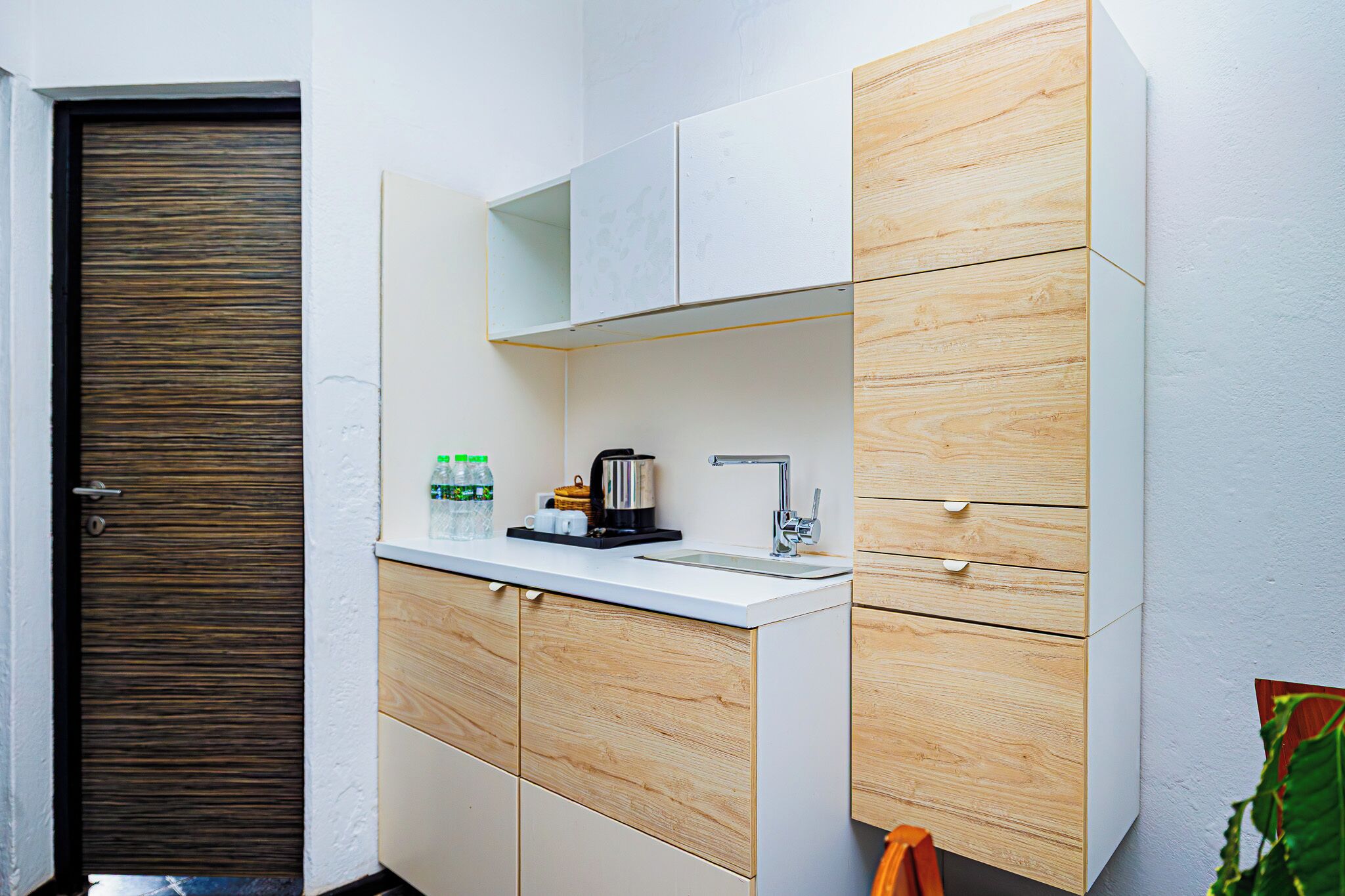 Una cocina compacta con un mueble de madera, una encimera blanca y un lavabo integrado.
