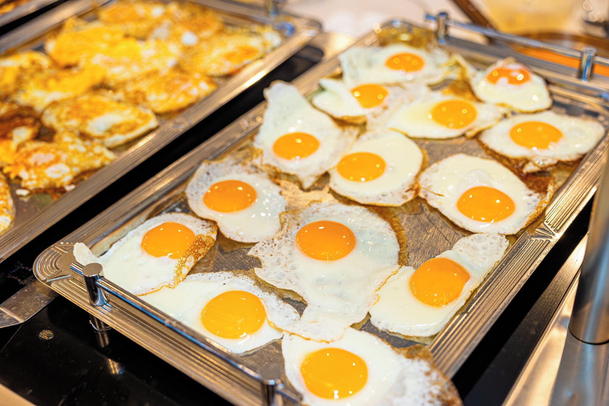 Un bufé con diversos platillos, incluyendo huevos fritos y otras opciones.