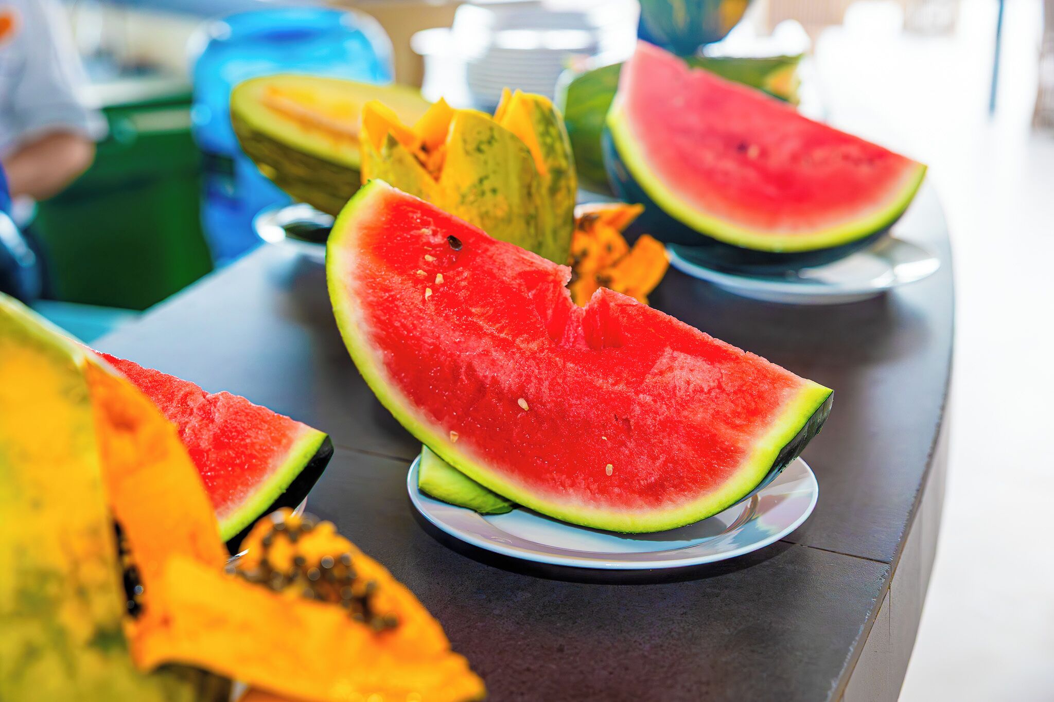 Uma mesa com diversas frutas, incluindo melancia e mamão.