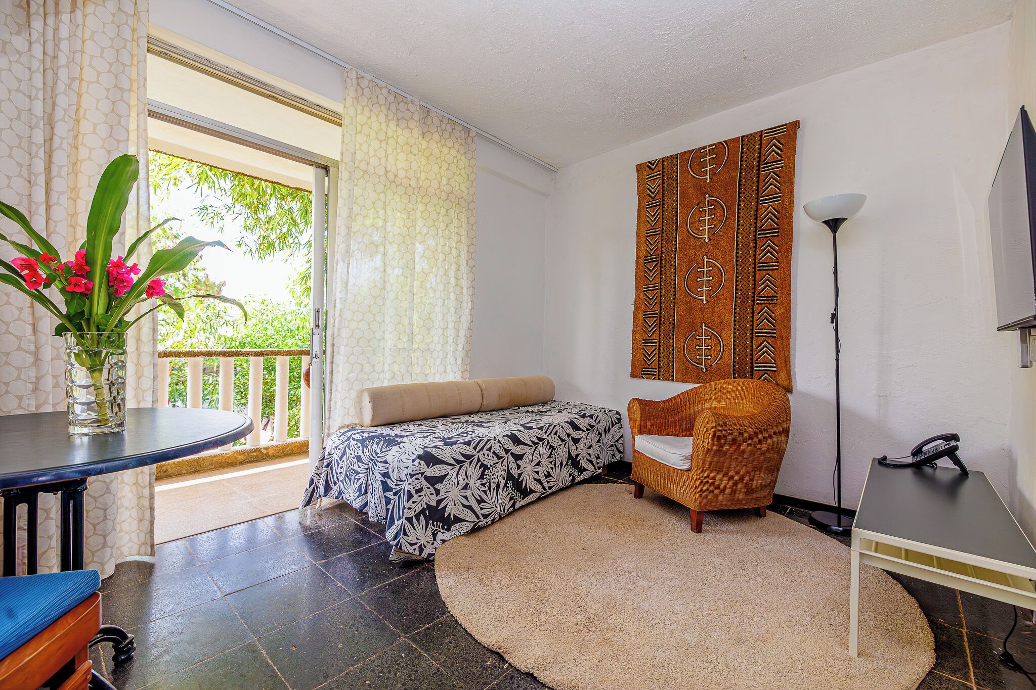 A room with a bed, a chair, a table, and a lamp.