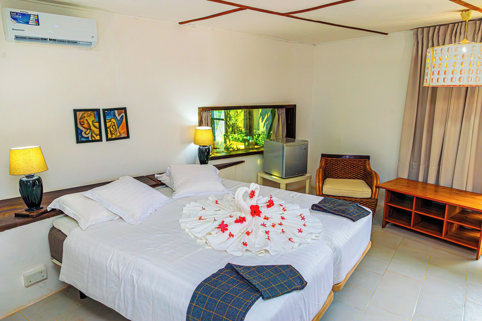 Quarto de hotel com uma cama grande, televisão, cadeira e escrivaninha.