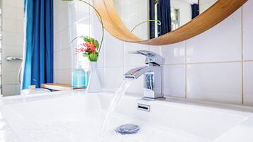 A bathroom with a modern sink, a wooden-framed mirror, and a blue curtain.