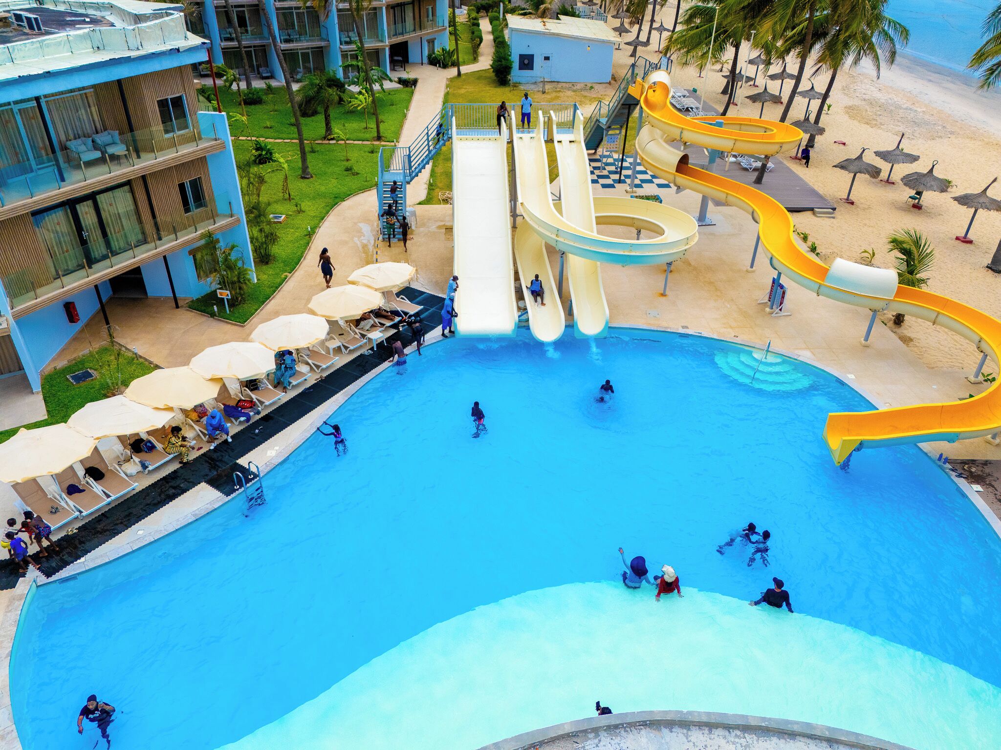 A large swimming pool with multiple slides, lounge chairs, and umbrellas.