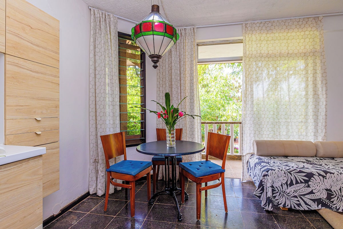 Una habitación con una mesa redonda, dos sillas, un sofá y una lámpara colgante.