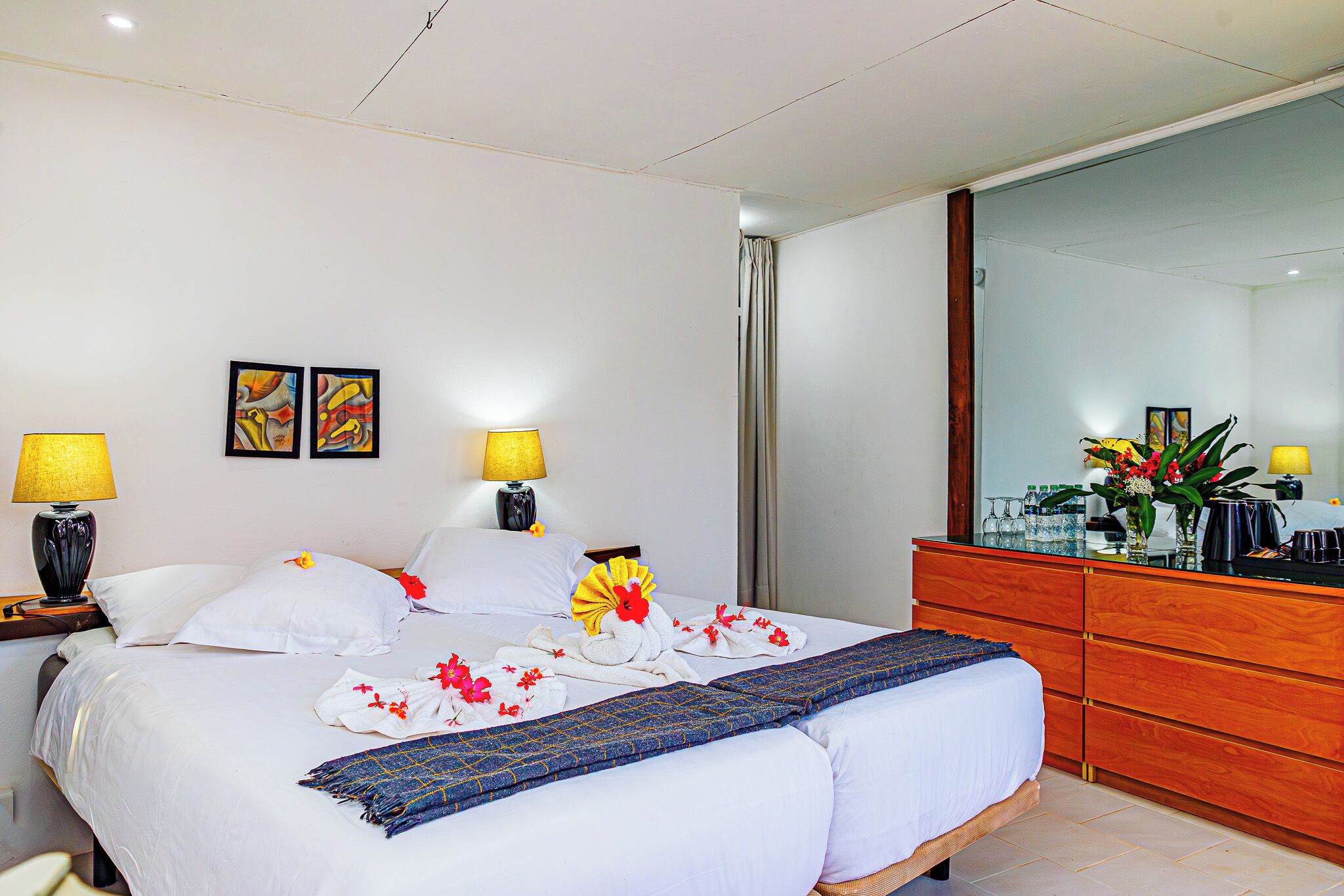 Una habitación de hotel con cama, dos lámparas de noche, un tocador de madera y un espejo.