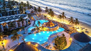 Een resort met een groot zwembad, palmbomen en toegang tot het strand.