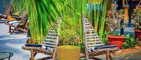 A tropical outdoor seating area with wicker lounge chairs and a woven stool.
