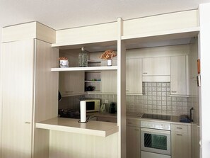 A compact kitchen with built-in appliances, including a microwave, oven, and dishwasher, and a small countertop area with a vase and decorative items. - Blumenweg 2/1 Appartement/Fewo 2-Bettwohnung by Interhome (Engelberg)