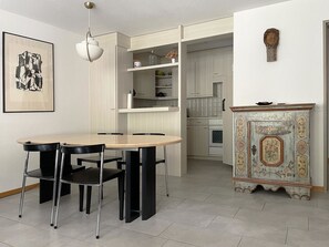 A dining area with a table and chairs, a cabinet with decorative elements, and a kitchen in the background. - Blumenweg 2/1 Appartement/Fewo 2-Bettwohnung by Interhome (Engelberg)