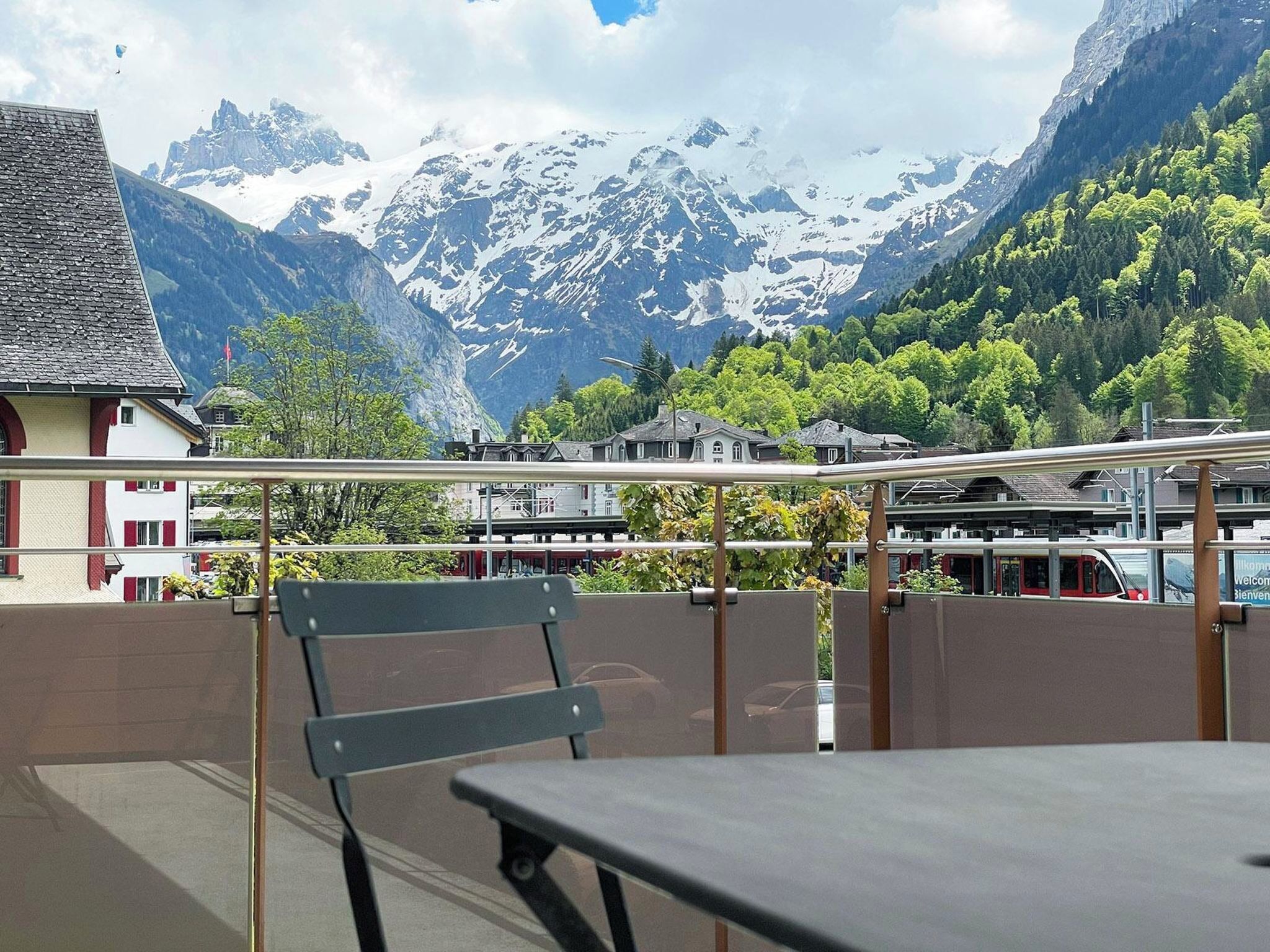 Een balkon met uitzicht op besneeuwde bergen, een tafel en een stoel.