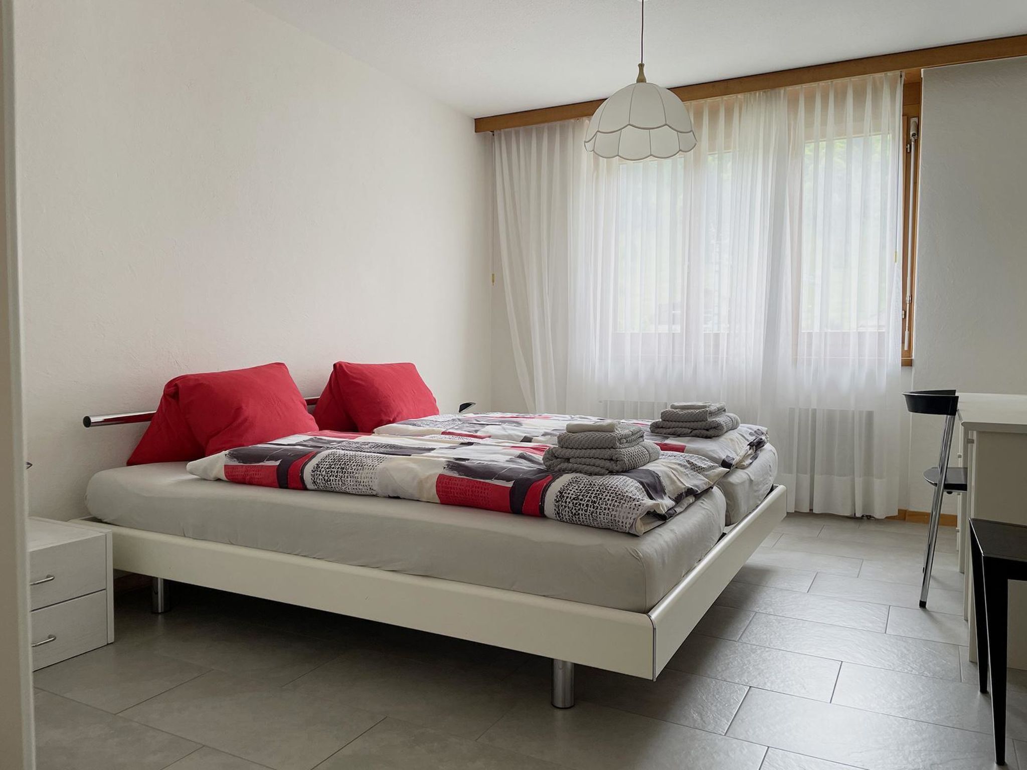 Une chambre à coucher moderne avec un lit, des oreillers, un bureau et une chaise.