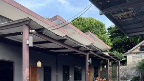 Un espacio de estar al aire libre con techo, mobiliario de madera y piso de baldosas.