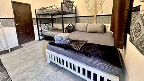 Una habitación con literas, una cama con dosel, un banco blanco y una hamaca.