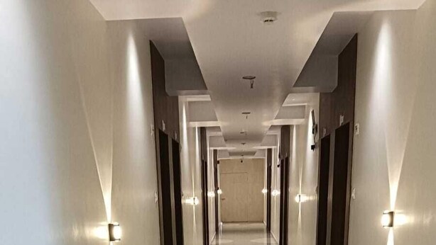 A long, well-lit hallway with a shiny floor, leading to a door at the end. - Hotel Empire (Vapi)