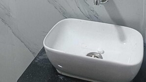 A bathroom with a marble wall, a wooden mirror, and a white sink. - Hotel Empire (Vapi)