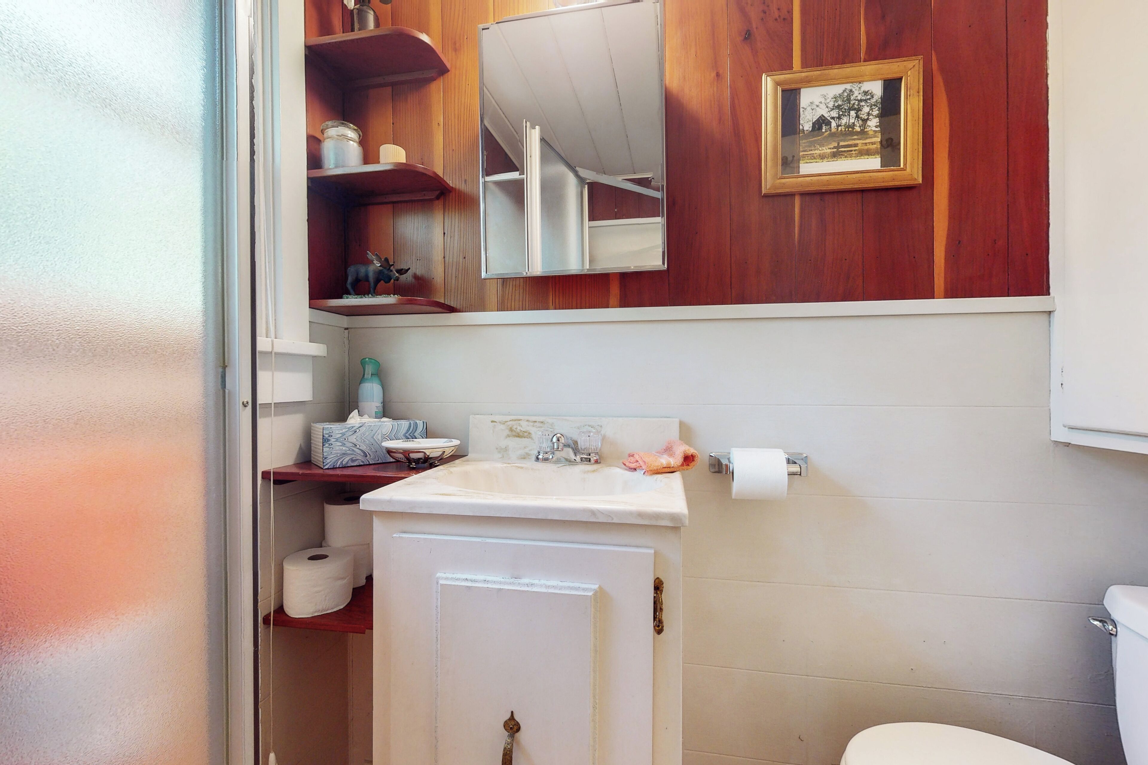 Un baño con tocador de madera, un espejo, un lavamanos y un inodoro.