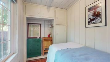 A bedroom with a bed, a green dresser, a wooden cabinet, and a framed picture on the wall.