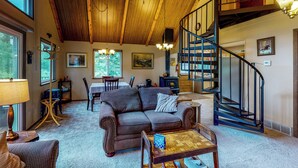 Un salón espacioso con techo de madera, una escalera y un comedor.