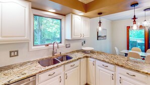 A kitchen with white cabinets, granite countertops, a double sink, and pendant lighting. - Dog-Friendly Yard! Family Retreat in Fort Wayne (Fort Wayne)