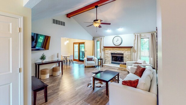 A spacious living room with a fireplace, a ceiling fan, and a large clock on the wall. - Dog-Friendly Yard! Family Retreat in Fort Wayne (Fort Wayne)