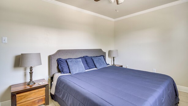 Ein Schlafzimmer mit einem Bett, zwei Nachttischen mit Lampen, einem Deckenventilator und einer Steckdose.