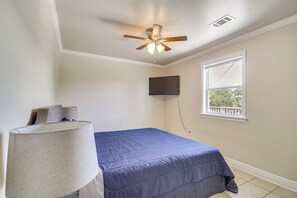 Une chambre à coucher avec un lit, un ventilateur de plafond, un téléviseur fixé au mur et une fenêtre donnant sur un beau paysage.