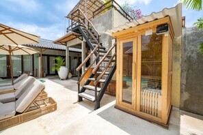 A spa area with a wooden sauna, a staircase, lounge chairs, and a pool. - Kano Twin (Canggu)