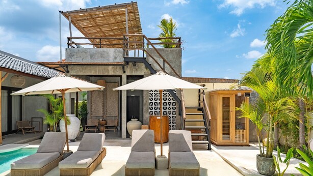 A poolside area with lounge chairs and umbrellas, a staircase, and a wooden structure with a thatched roof. - Kano Twin (Canggu)