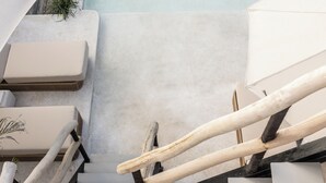 A staircase with white cushioned steps and a wooden handrail. - Kano Twin (Canggu)
