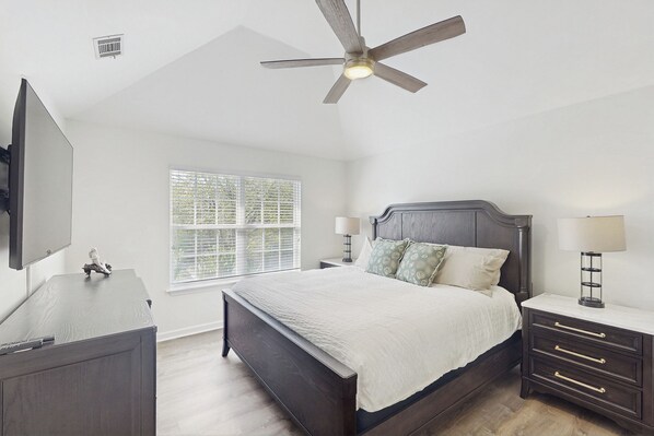 A bedroom with a bed, nightstands, a desk, a ceiling fan, and a window with blinds. - Private Pool: Quiet Family Home in Savannah (Savannah)