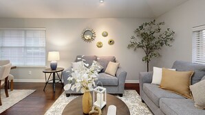 Un salon avec un canapé gris, une table basse ronde et une lampe.