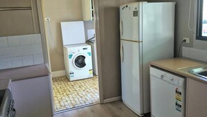 Una cocina compacta con lavadora, refrigerador y lavavajillas.