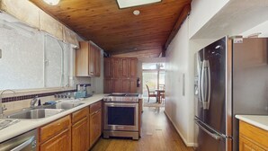 Una cocina con armarios de madera, electrodomésticos de acero inoxidable y suelo de madera.