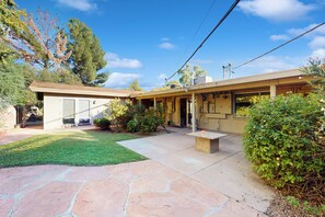 A single-story house with a covered patio, a small garden, and a clear blue sky. - Poolside Oasis! Phoenix Group Sanctuary w/ Patio (Phoenix)