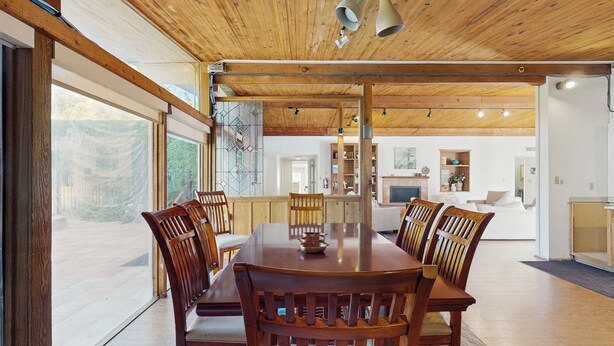 Un comedor amplio con una mesa y sillas de madera, un ventanal y vistas al exterior.
