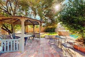 A covered patio area with outdoor seating and a pool in the background. - Poolside Oasis! Phoenix Group Sanctuary w/ Patio (Phoenix)