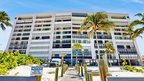 Un hotel a più piani con un cortile interno, circondato da palme e una spiaggia di sabbia.