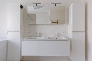 Un baño moderno con dos lavamanos, un espejo y una ducha.