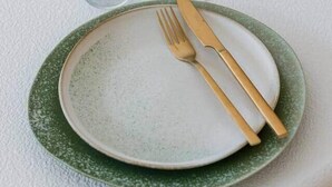 A dining table with a green plate, gold cutlery, and a glass. - Brand new house Sable d'Or  - Oostduinkerke (Koksijde)