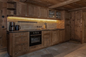 A wooden kitchen with a built-in oven, a coffee maker, and a knife block. - Luxury Detached Panoramic Mountain Home (Tschagguns)