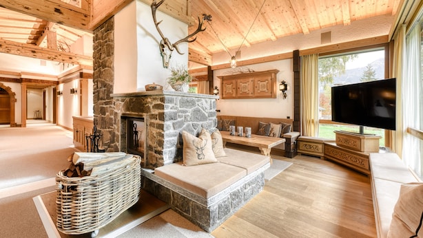 Una sala de estar acogedora con chimenea de piedra, un televisor grande y una pared de piedra.