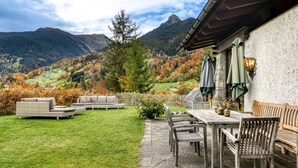 Un patio con suelo de piedra, mobiliario exterior y vistas a un paisaje montañoso.