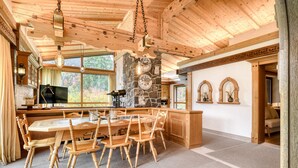 Un interior de madera con una mesa de comedor, sillas, detalles de piedra y ventanas amplias.