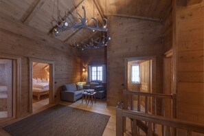A log cabin interior with a bed, sofa, and dining table. - Panorama Deluxe Mountain Hideaway House (Tschagguns)