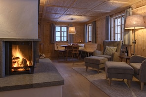 A cozy room with a fireplace, wooden furniture, and a dining area. - Panorama Deluxe Mountain Hideaway House (Tschagguns)