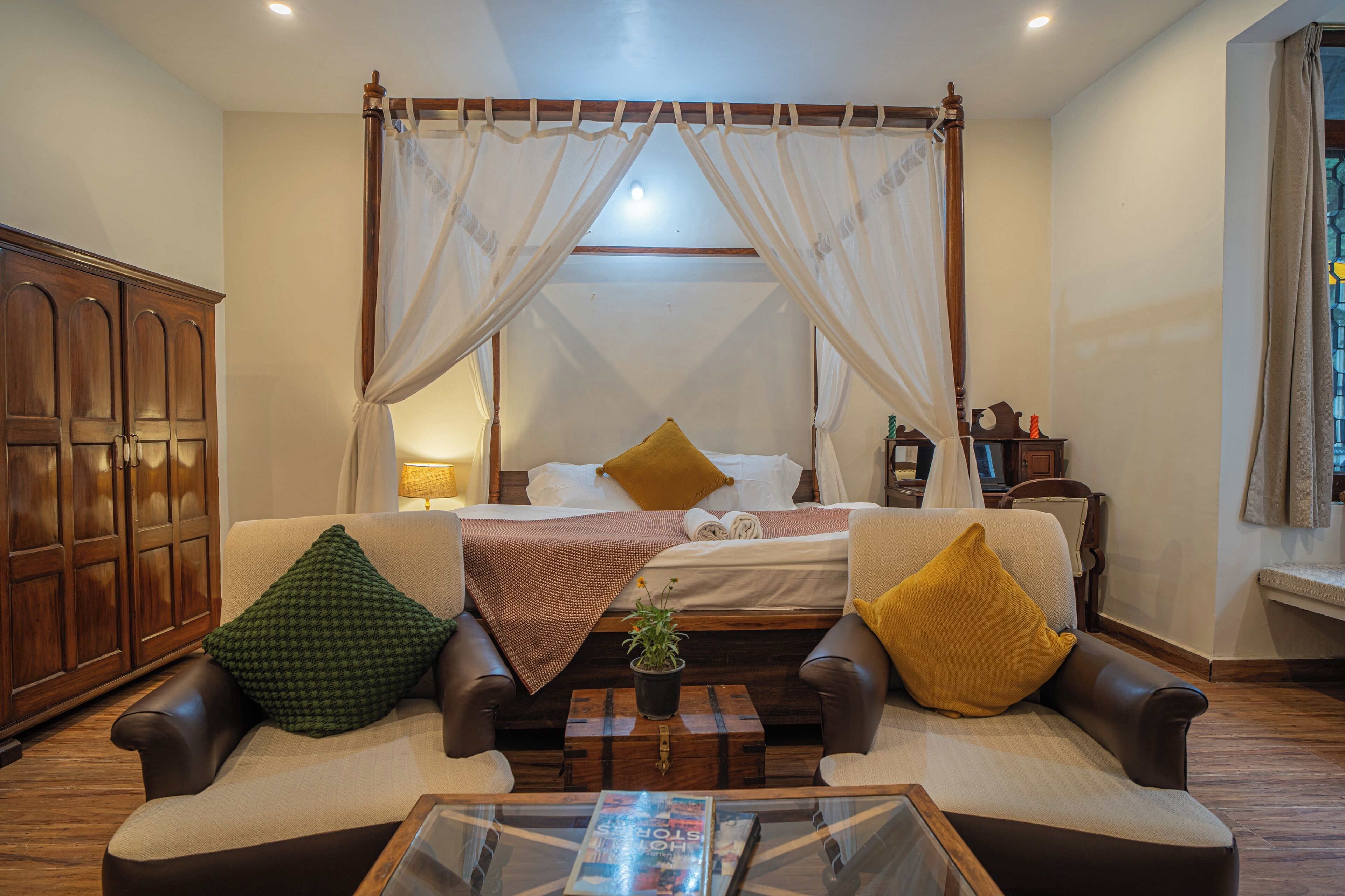 A bedroom with a canopy bed, a sofa, a coffee table, and a cabinet.