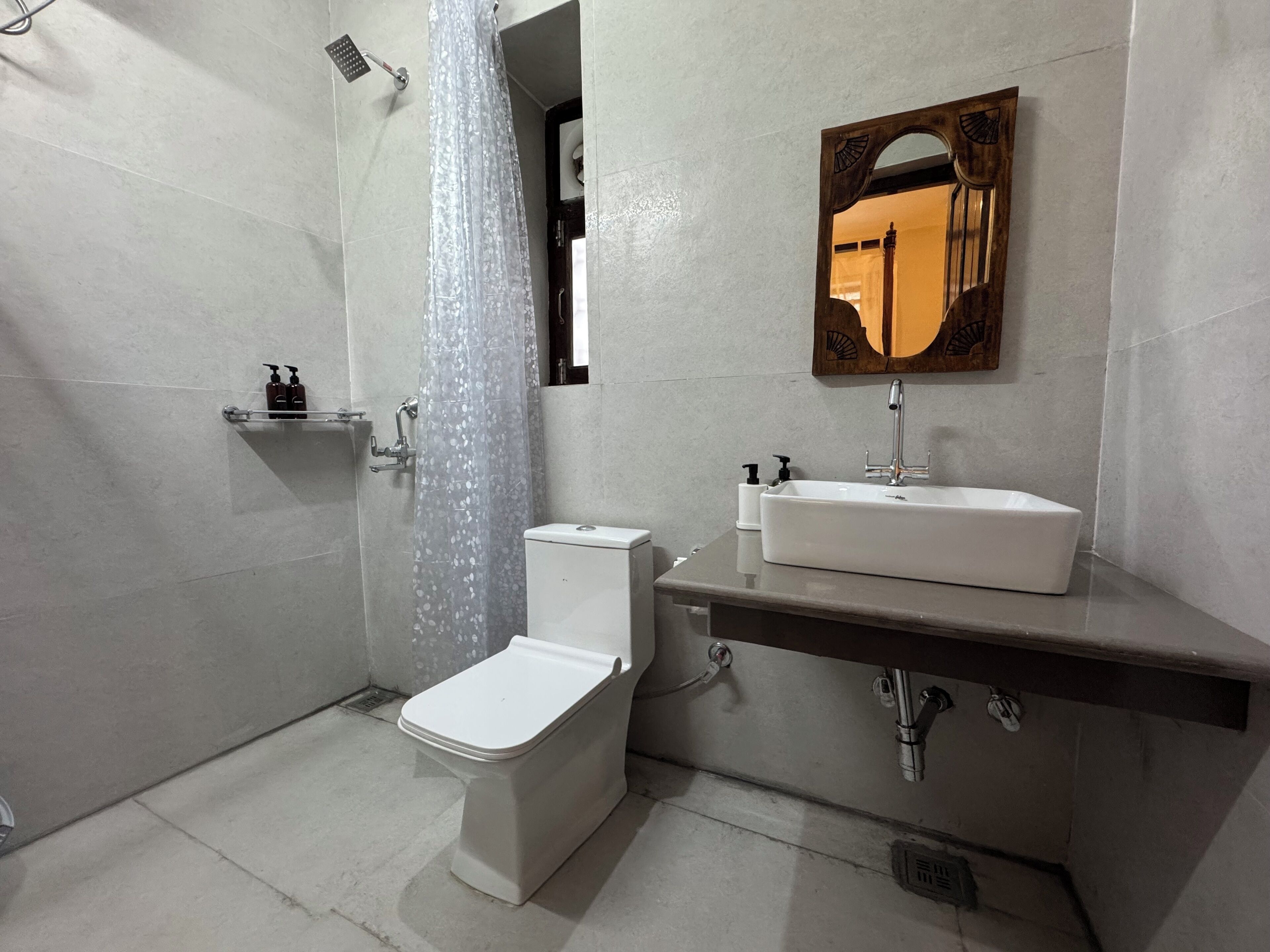A bathroom with a toilet, a shower, a sink, and a mirror.